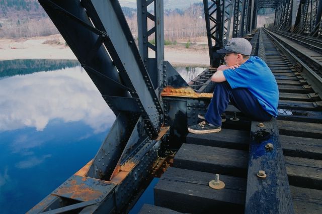 boy musing on a railroad bridge