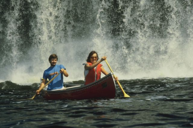 canoeing at the base of a waterfall